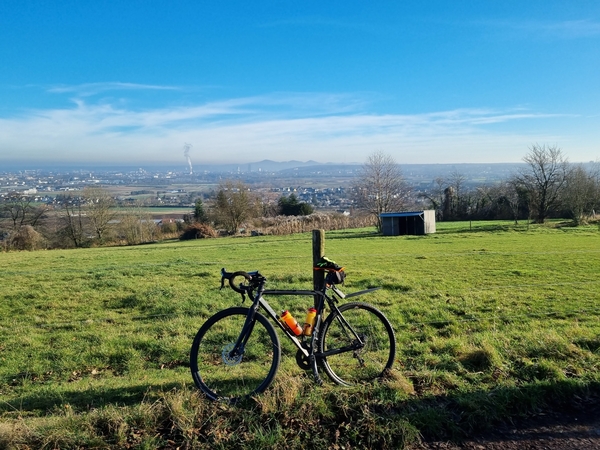Eine Aufnahme von einem Fahrrad, welches an einem Pfosten, an einem Feld lehnt