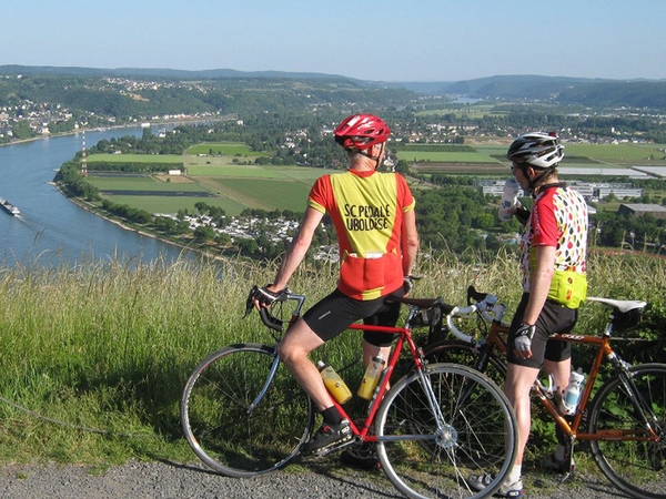 Zwei Radfahrer blicken von einer Erhöhung in Richtung Rhein, Bild von Uli Sander.