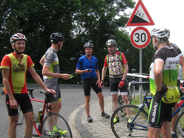 Mehrere Fahrradfahrer stehen an einer Straße.