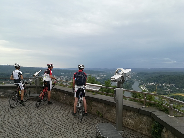 Mehrere Fahrradfahrer stehen auf einer Erhöhung und blicken auf den Rhein, Bild von David Schumacher und Lennart Ulbrich.