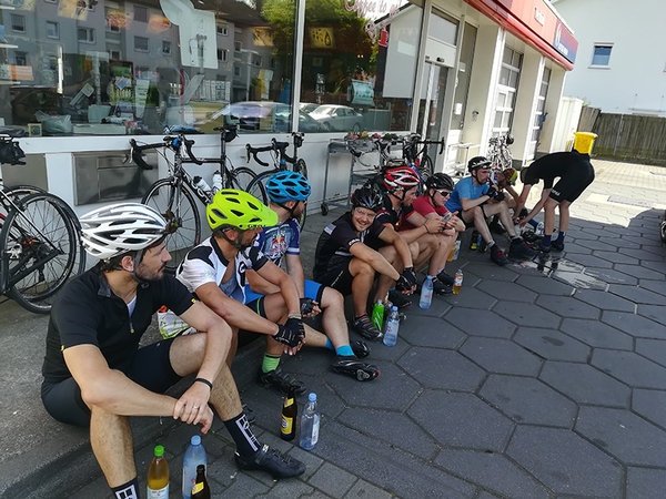 Mehrere Fahrradfahrer sitzen vor einem Laden.