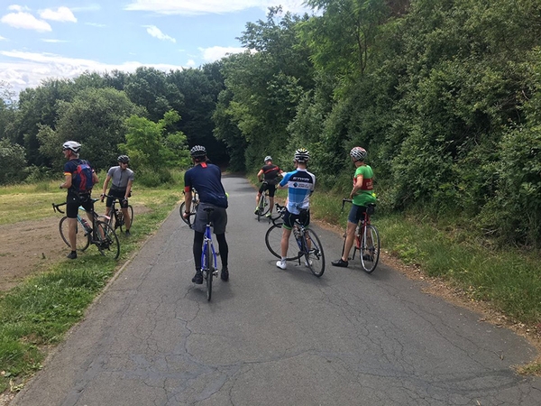 Mehrere Fahrradfahrer stehen an einer Straße in der Natur.