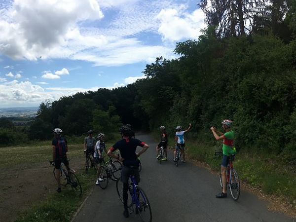 Mehrere Fahrradfahrer stehen an einem Feldweg und machen Fotos.