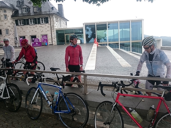 Mehrere Fahrradfahrer stehen vor einem Gebäude.